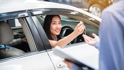 Car Dealership. The Asian woman receiving a car key with a smile form the salesman before hand over. Auto Leasing Business. Automotive Leasing and Dealing Business. International Business.