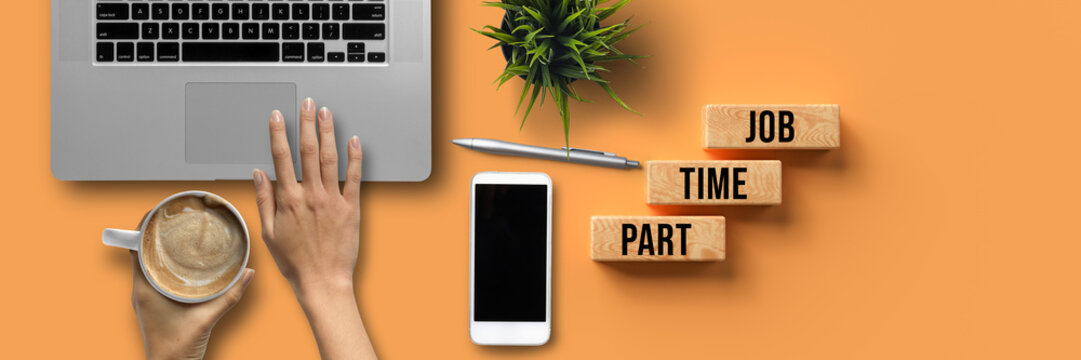 hand over a computer with coffee and office equipment and message PART TIME JOB on orange background