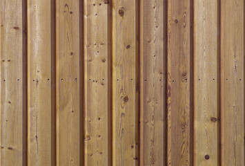A close-up of a fragment of a wall made of vertical strug wooden planks. Horizontal orientation, front view. Selective focus. Wooden texture, background.