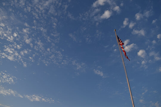 American Flag Flying Against Blue Sky With White Clousd