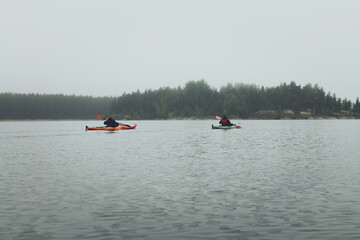 Fototapeta na wymiar Unrecognized men in kayak. Summer trip on Ladoga lake in Karelia.