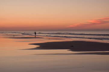 Naklejka premium Person Standing at Shoreline Watching Waves at Dawn Pre-Sunrise