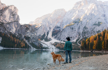 man with a dog at the famous mountain lake Braies in Italy. Traveling with a pet.