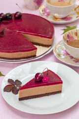 Teatime with No-bake chocolate mousse cake with sweet cherry  jelly, decorated with sweet cherries, blackberries and flowers on pink table cloth.