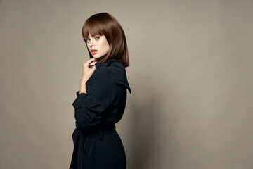 Woman in a black dress on a beige background and brown hair free place