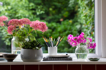 Window sill with paintbrushes and flowers
