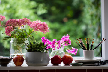 Window sill with paintbrushes and flowers
