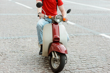 Fototapeta premium Beautiful retro style scooter. Man having a ride in the city