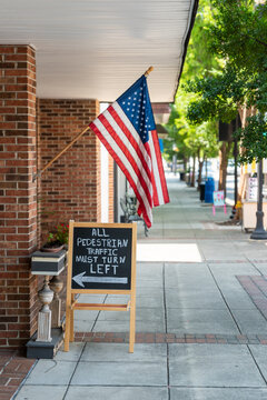 American Flag hangs on a sidewalk store front.