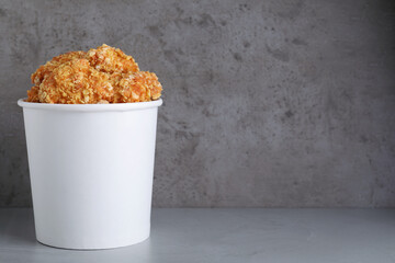 Bucket with yummy nuggets on grey table, space for text
