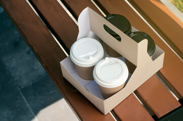 Cardboard cup of coffee on bench, take away concept