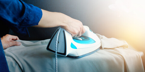Closeup of woman ironing clothes on ironing board. High quality photo