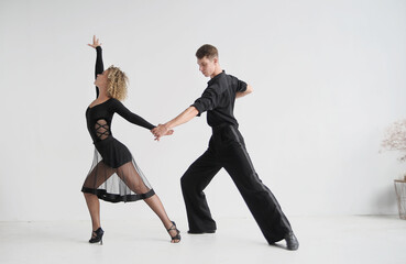 Beautiful couple in stylish black costumes dancing ballroom dances