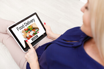 Girl ordering pizza online on smartphone, with table and coffee and plant in background