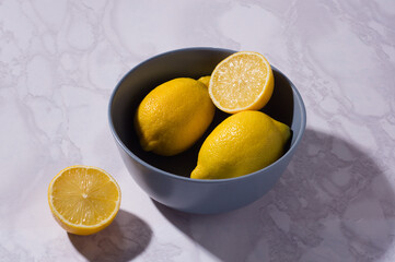 sliced and whole lemons on a white table and in blue bowl. Vitamin C concept. White background