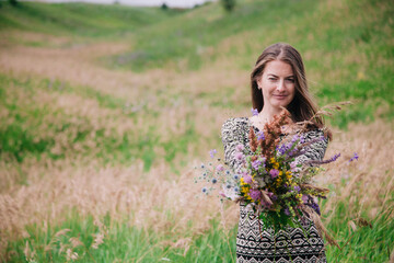Beautiful, slender girl in a meadow dress with wildflowers