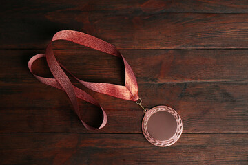 Bronze medal on wooden background, top view. Space for design