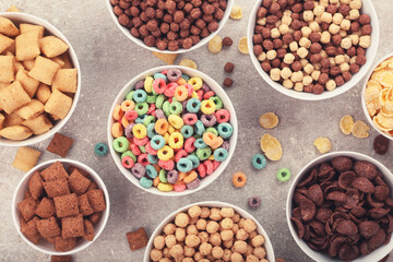 Various corn flakes in bowls on grey background