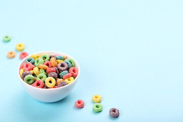 Colorful corn rings in bowl on blue background