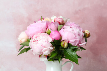 Bouquet of beautiful peonies in vase on pink background, closeup