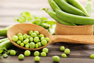 Fresh peas in spoon on brown wooden table