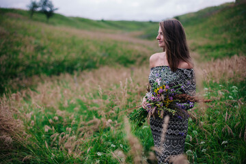 Beautiful, slender girl in a meadow dress with wildflowers