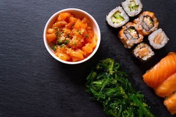 Assorted plate of sushi on black slate plate.