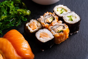 Assorted plate of sushi on black slate plate.