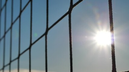 Volleyball net in the sand background close-up. The beach volleyball court is closed by the coronavirus. Sunset through the volleyball net