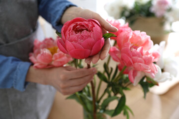 Florist making beautiful peony bouquet at table, closeup © New Africa