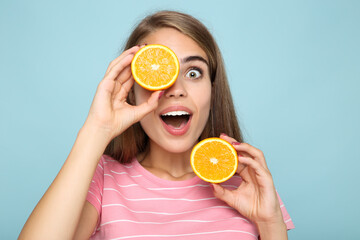 Young girl with fresh orange fruit on blue background