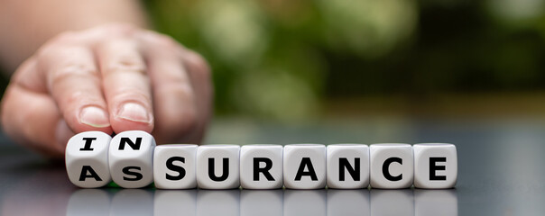 Hand turns dice and changes the word assurance to insurance.
