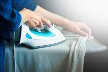 Close up of woman ironing clothes on ironing board.