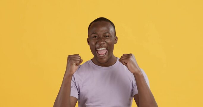 Excited black man shouting for joy, shaking fists and screaming