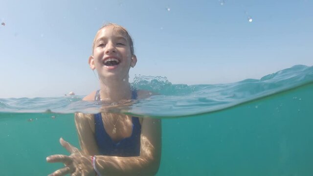 Cute child girl bathes in sea. She is learning to swim. Family vacation concept.