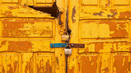 the old yellow door is closed with a padlock