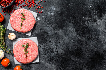 Burger patties, raw fresh ground, mince meat. Black background. Top view. Copy space