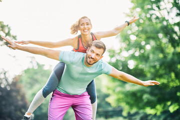 fitness woman park exercise lifestyle outdoor sport healthy couple nature active young fit fun piggyback