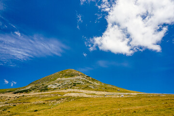 Fototapeta premium Mountain peak near the Transalpina high altitude road in Parang mountains in Romania, in the summer, with blue sky and clouds