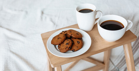 Breakfast in bed. Hot coffee with oatmeal cookies with chocolate on a wooden tray.