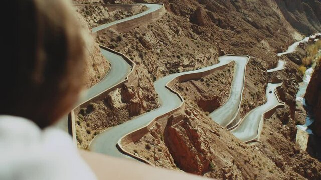 Panoramic view of windy mountain road in the Dades Gorge, Gorges Du Dades, Morocco, point of view from woman back, 4k
