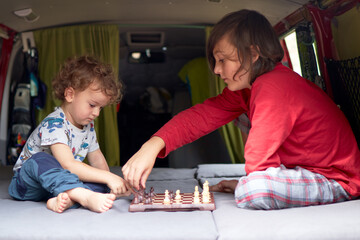 Two kids playing chess in a camper van