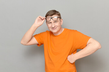 Portrait of happy mature man with glasses, wearing orange T-shirt