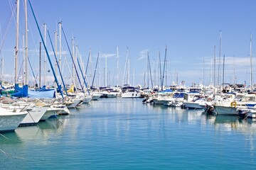 Obraz premium Yachts and speed boats at harbor. Yachts moored in the port. Ocean Coast pier. High class lifestyle. Yachting. Expensive toys. Sea ​​transport. Nautical. Yachting sport. Expensive yachts at the pier.