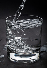 Water flows in glass on a dark background
