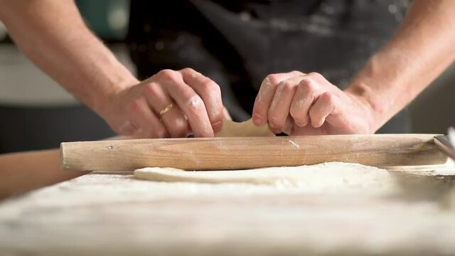 Man cooks pizza. Prepering ingredients for pizza.Roll out the dough with a rolling pin