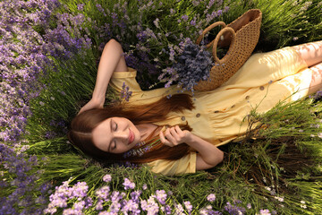 Young woman lying in lavender field on summer day, top view