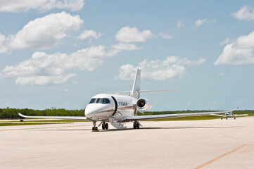 front view, far distance of a private jet plane loading before take off, from a tropical airstrip, on sunny day,