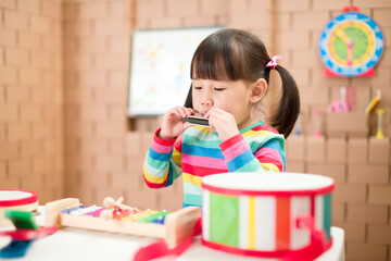 toddler girl play harmonica at home for homeschooling