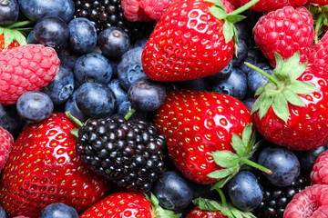 Fototapeta na wymiar Mix of different ripe tasty berries as background, top view